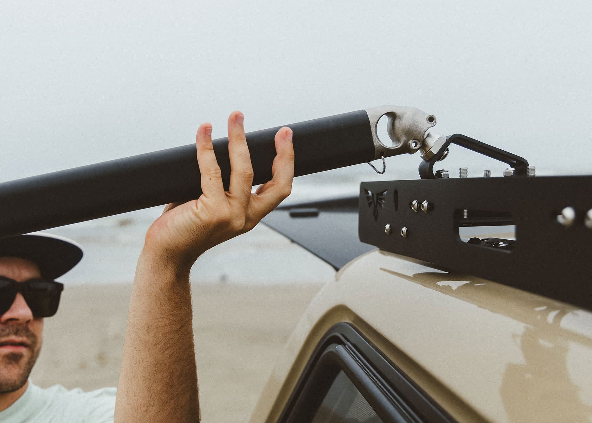Person holding a roof rack on a vehicle in a desert setting