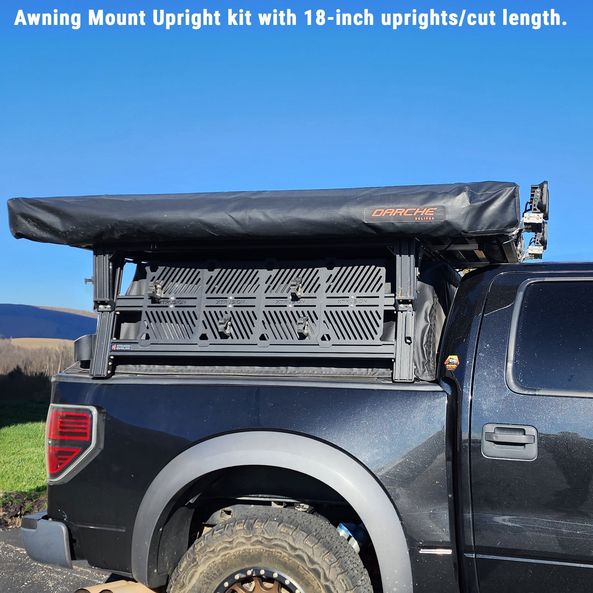 Black truck with an open roof rack and Darche branding against a blue sky.
