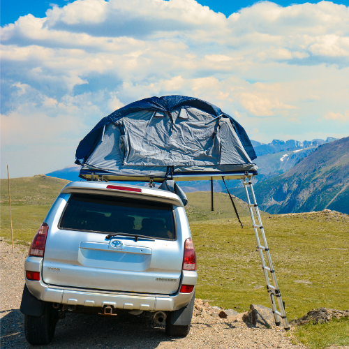 Silver SUV with a rooftop tent in a mountainous landscape